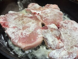 pork chops frying one side